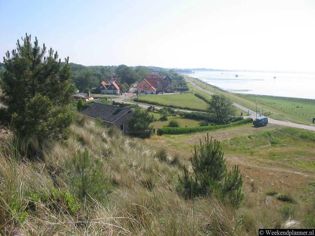 Vanaf het duin heb je een mooi uitzicht over Oost-Vlieland. In de verte zie je de veerboot aanleggen.   De attracties van Vlieland.