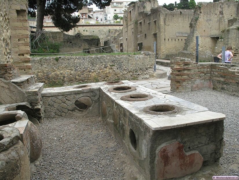 Dit zijn de overblijfselen van een Thermopolium, een eethuis. Veel armen aten hier omdat die geen eigen keuken hadden. Op de gaten werd gekookt.
