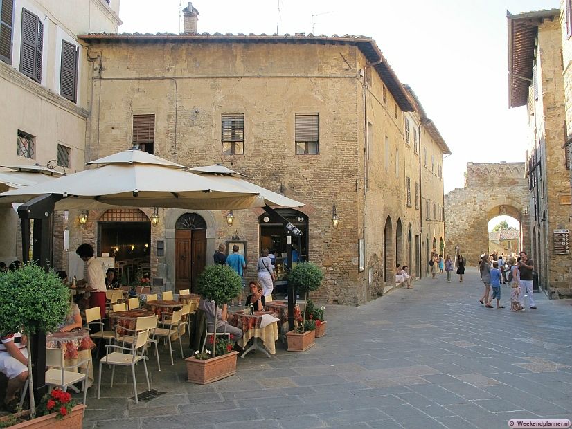 Op de achtergrond zie je één van de 13de-eeuwse stadspoorten.  De middeleeuwse straatjes van San Gimignano zijn bijna autovrij. Je kunt buiten de stadsmuren parkeren op één van de parkeerplaatsen. 