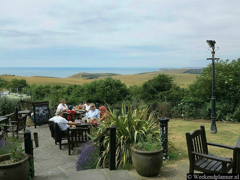Het terras van de pub en restaurant The Beachy Head. Op de achtergrond zie je de vuurtoren op de krijtrots van Beachy Head.Tip: De  attracties van Beachy Head.