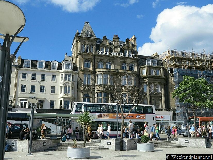 In New-Town zijn de straten breed en de meeste gebouwen hebben de in de 18de eeuw gangbare Greorgiaanse bouwstijl. Foto: De winkelstraat Princes Street bij de uitgang van treinstation Waverley Station.Tips: De attracties van New Town Edinburgh.