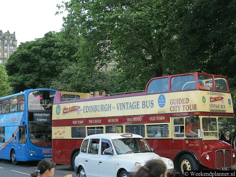 De blauwe bus vanaf het vliegveld heeft een halte op Princes Street. Op de voorgrond zie je een Hop-on Hop-off bus van Mac Tours. De bestemmingen lees je op de zijkant van de bus.