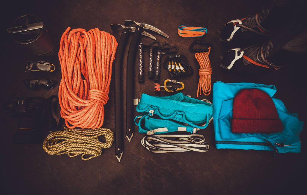 Dit is een klimuitrusting. Je ziet o.a. touwen, stijgklemmen, karabiners, schoenen met losse stijgijzers, ijsbijlen en een zonnebril die 100% UV-werend is.